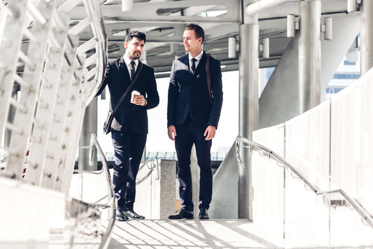 Two smiling businessman coworkers in black suit talking and walking.business people discussing strategy in the modern city