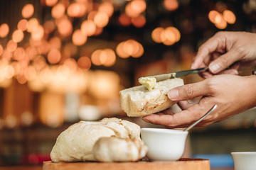 Appetizer food ; Bread and butter serve on wooden plate. Male use the knife and butter to prepare food