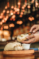 Appetizer food ; Bread and butter serve on wooden plate. Male use the knife and butter to prepare food