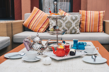 Traditional English afternoon tea: chocolate lava and chocolate hand made like a red jar with various sandwiches on the background, selective focus