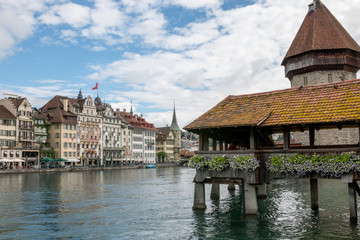 Fototapeta na wymiar Lucerne, Switzerland - July 3, 2017: Panoramic view of city center of Lucerne with famous Chapel Bridge and river Reuss. Summer landscape, sunshine weather, dramatic sky and sunny day