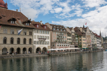 Fototapeta na wymiar Lucerne, Switzerland - July 3, 2017: Panoramic view of city center of Lucerne and river Reuss. Summer landscape, sunshine weather, dramatic blue sky and sunny day