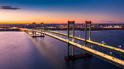 Aerial view of Delaware Memorial Bridge at dusk. The Delaware Memorial Bridge is a set of twin suspension bridges crossing the Delaware River between the states of Delaware and New Jersey - obrazy, fototapety, plakaty