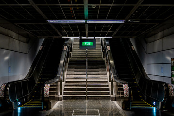 Underground stair way and escalators with a green exit sign
