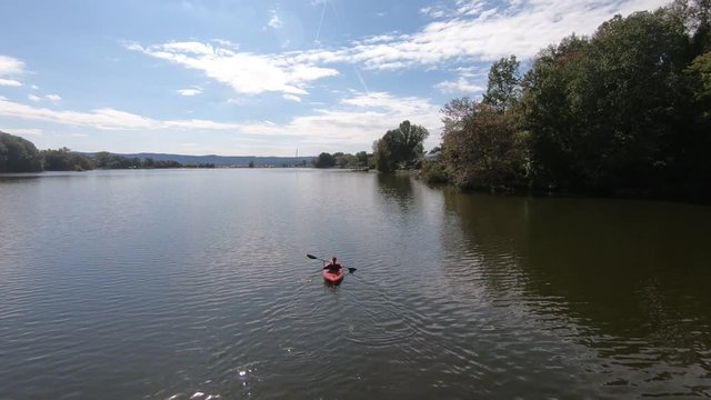 Aerial View Of A Kayak In A Lake On A Sunny Day. Drone Flies Overhead And Zooms Past.