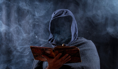 a man hides his face and reads in a book - obrazy, fototapety, plakaty