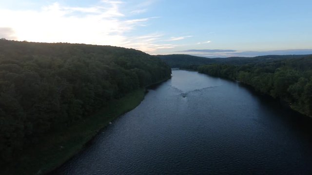 Aerial view of river and forest. Descending shot towards shipwreck in fast moving water.