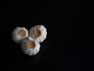 Three garlic on black background with dark tone, copy space