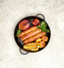 grilled juicy sausages in a pan on a gray background.