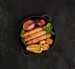 grilled juicy sausages in a pan on a black background