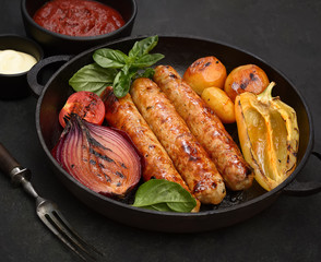 grilled juicy sausages in a pan on a black background