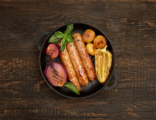 grilled, juicy sausages in a pan on a wooden background