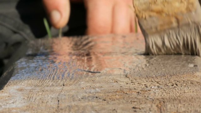 Man hammering used long nail into old boards