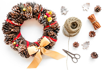 Preparing to Christmas. Christmas wreath made of pine cones near decorative elements on white background top view