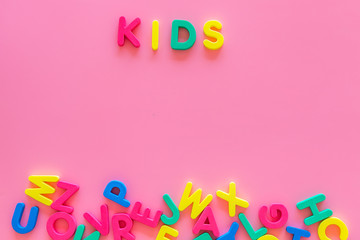 Fototapeta na wymiar Early childhood development concept. Word kids written by plastic letters of toy alphabet on pink background top view copy space