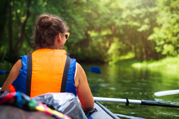 kayaking and canoeing. Young woman in boat with oars swims on wild river in jungle