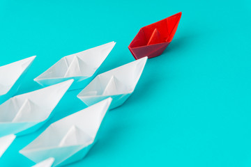 White and red paper boat or ship in one direction on blue background. Business for innovative...
