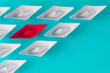 White and red paper boat or ship in one direction on blue background. Business for innovative...