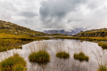 Clouds and mountain peaks reflection in the Dolomite Alps