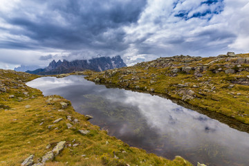 Naklejka na ściany i meble Clouds and mountain peaks reflection in the Dolomite Alps