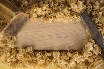 Chisel and wooden hammer on a piece of oak wood covered in shavings
