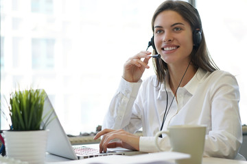 Female customer support operator with headset and smiling.