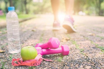 Exercise and fitness diet concept, dumbbell with green apple and water on road of sport man