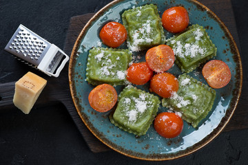 Above view of spinach ravioli with cherry tomatoes and grated parmesan cheese, studio shot