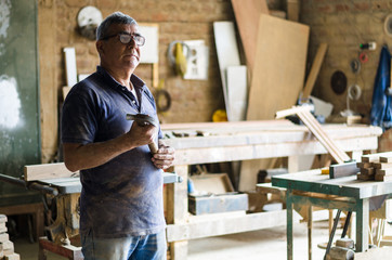 Portrait of senior carpenter. Standing with the background of your carpentry behind