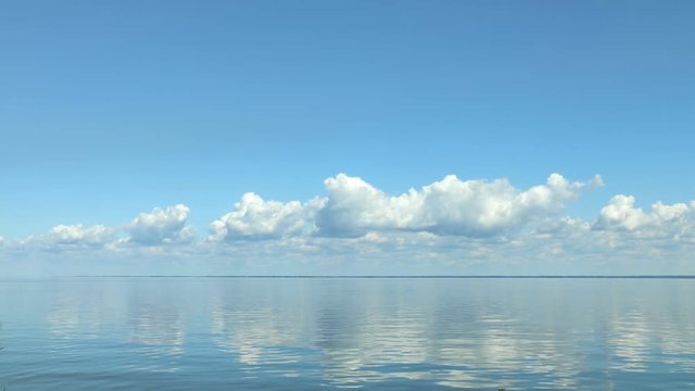 Amazing beautiful blue sky with light white clouds over calm smooth river surface. Summertime. Sunny day. Time-lapse HD video.