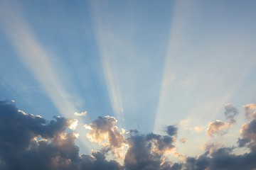 Sun rays shine through the clouds at sunset, natural sky background