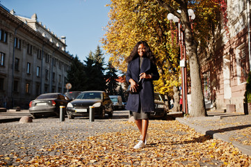 Stylish african american girl in blue coat posed at sunny autumn day. Africa model woman.