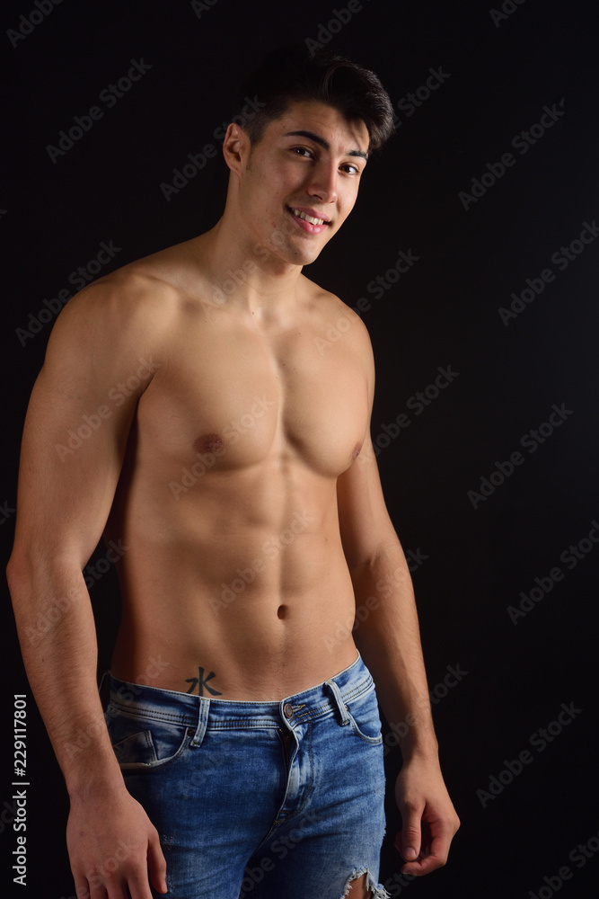 Wall mural portrait of young man with torso naked with jeans on black background