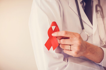 Doctor hand holding red ribbon, world AIDS day - obrazy, fototapety, plakaty