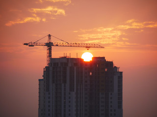 Silhouette of a building under construction against the rising sun. Construction site background.