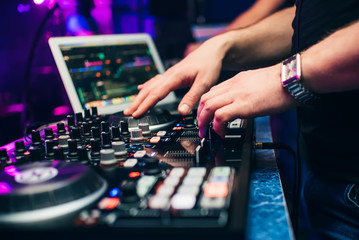 Fototapeta premium DJ in a booth playing a mixer at a nightclub at a party