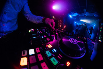 Obraz premium DJ plays with his hands on a music mixer in a nightclub
