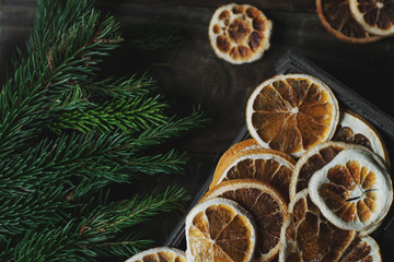 Cozy Christmas or New Year home decoration with fir tree and oranges on rustic wooden table, top view, selective focus