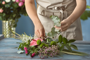 Female florist preparing bouquet of beautiful flowers at table
