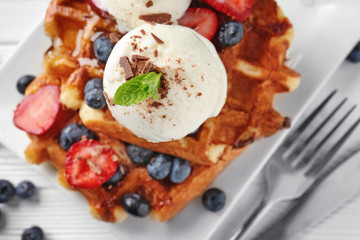Delicious waffles with berries and ice cream on plate, closeup