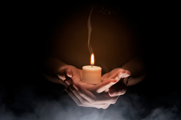 Obraz premium Ręce, trzymając świecę na ciemnym tle