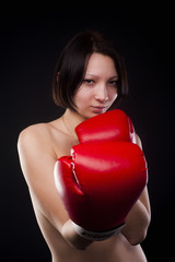 Half body portrait of sexy young brunette woman with red boxing gloves covering breasts, Isolated over black