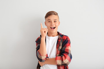 Emotional teenage boy with raised index finger on white background © Pixel-Shot