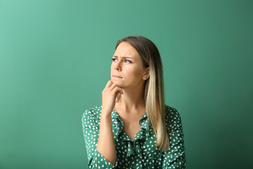 Thoughtful young woman on color background