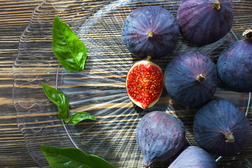 Plate with fresh ripe figs and basil on wooden table