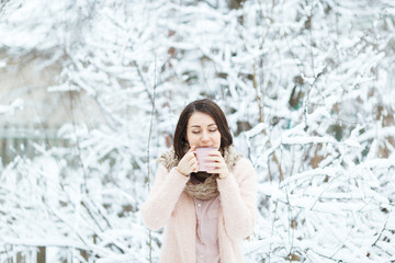 cute girl with a pink cup of coffee in the winter forest