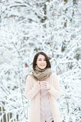 cute girl with a pink cup of coffee in the winter forest