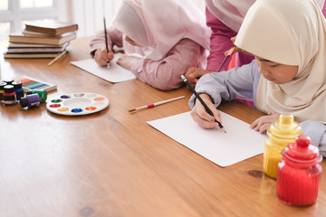 Muslim woman teaching her children painting and drawing at home.