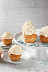 Plates and stand with delicious cupcakes on light table