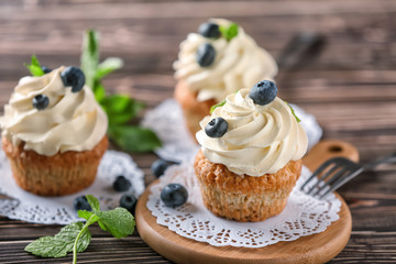 Delicious cupcakes with blueberries on wooden table